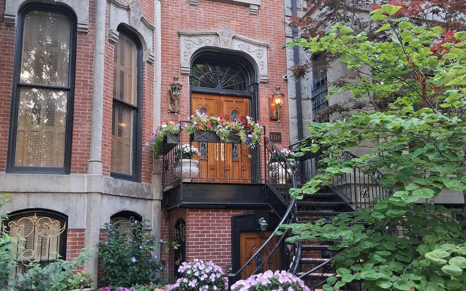 A brick Chicago townhouse with a wooden front door and flower boxes on the stairs